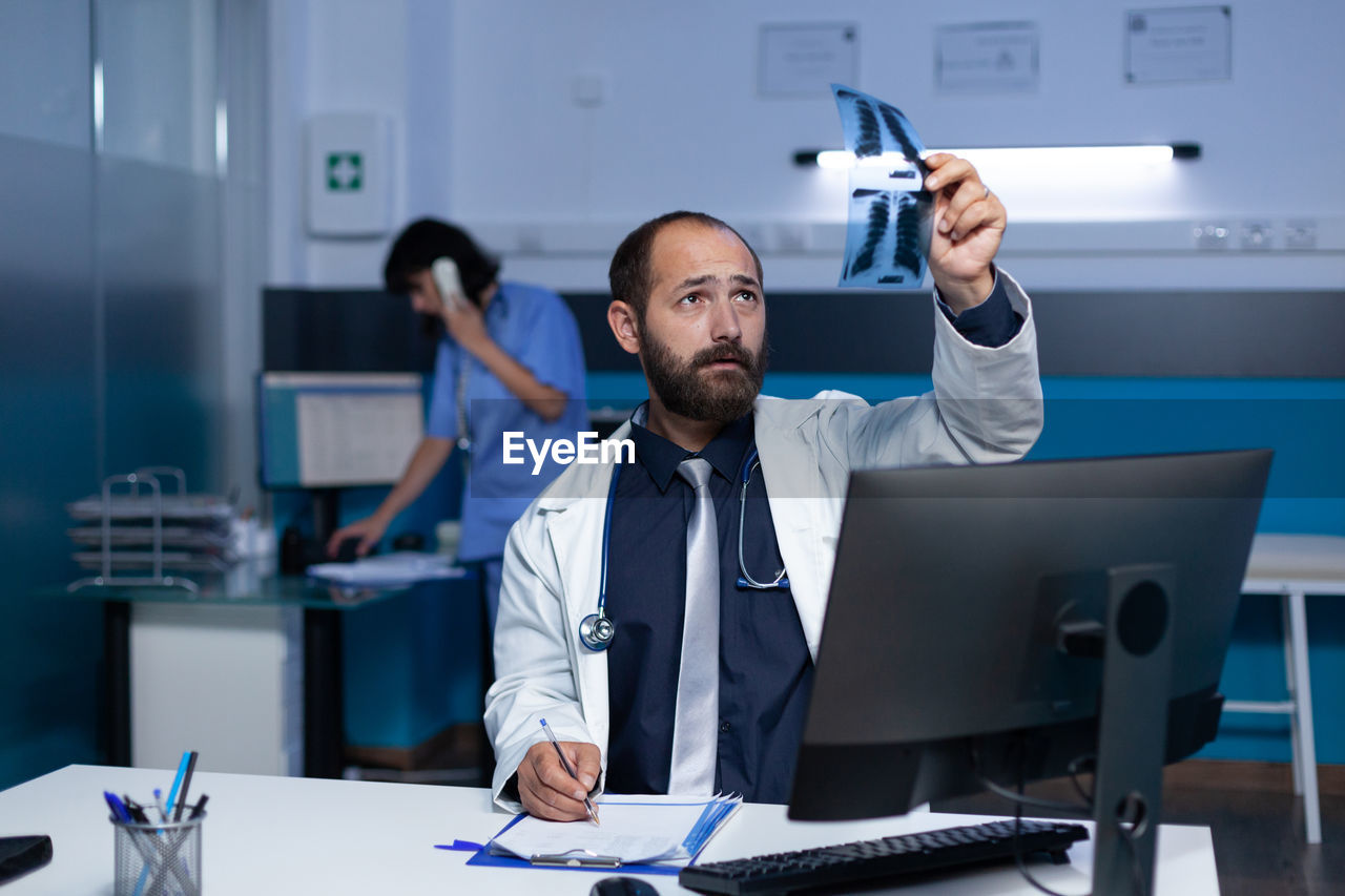 midsection of doctor working at desk in office