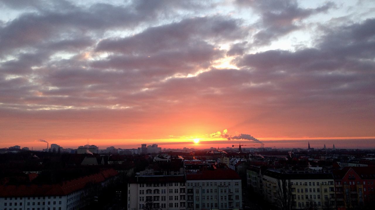 View of city against cloudy sky at sunset