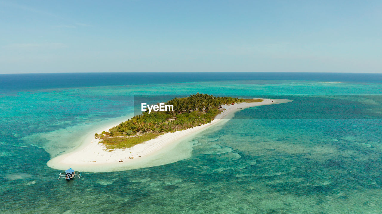Tropical island canimeran with sandy beach in the blue sea with coral reef. balabac, palawan, 