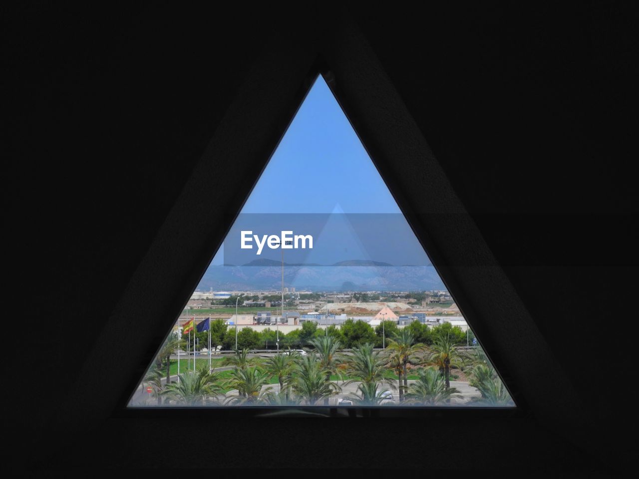 Landscape against clear blue sky seen through triangle shape window