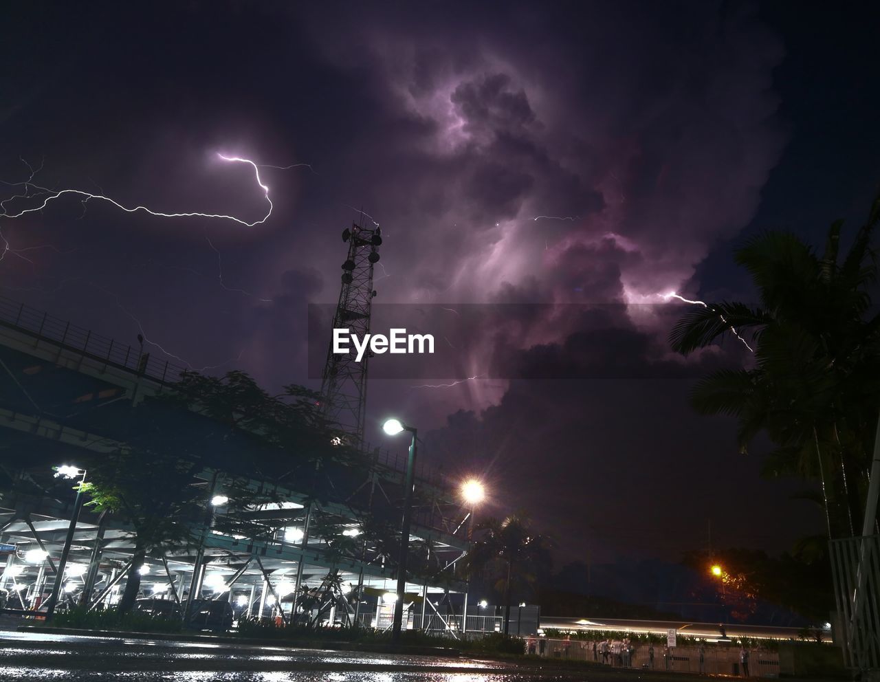 LOW ANGLE VIEW OF LIGHTNING OVER ILLUMINATED CITY AGAINST SKY