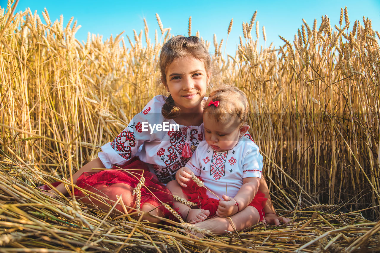 Girl sitting with sister in field