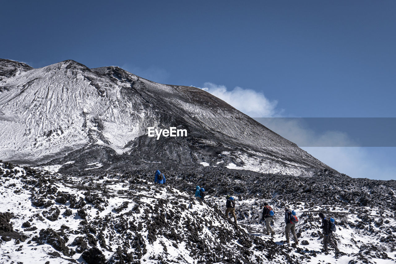 PEOPLE ON SNOWCAPPED MOUNTAINS AGAINST SKY