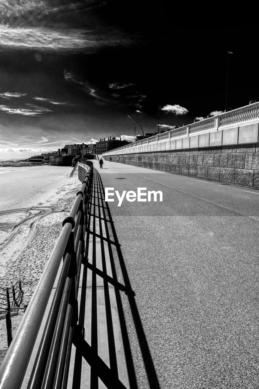 black and white, monochrome, monochrome photography, sky, transportation, nature, white, architecture, built structure, railing, black, the way forward, road, no people, darkness, bridge, outdoors, cloud, water, snow, line, diminishing perspective, land, day, vanishing point, city, environment