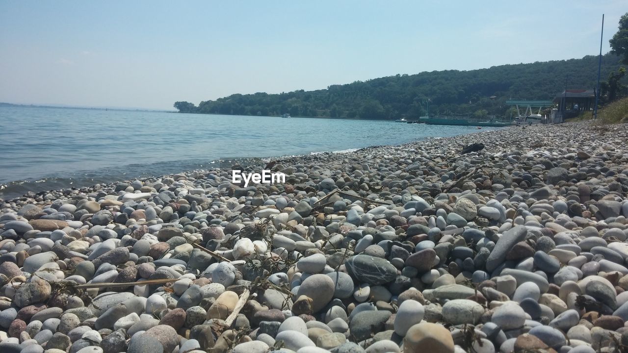PEBBLES AT BEACH AGAINST CLEAR SKY
