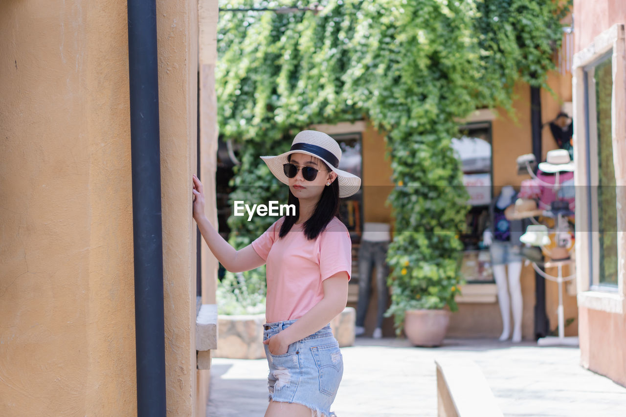 Portrait of young woman wearing hat while standing outdoors