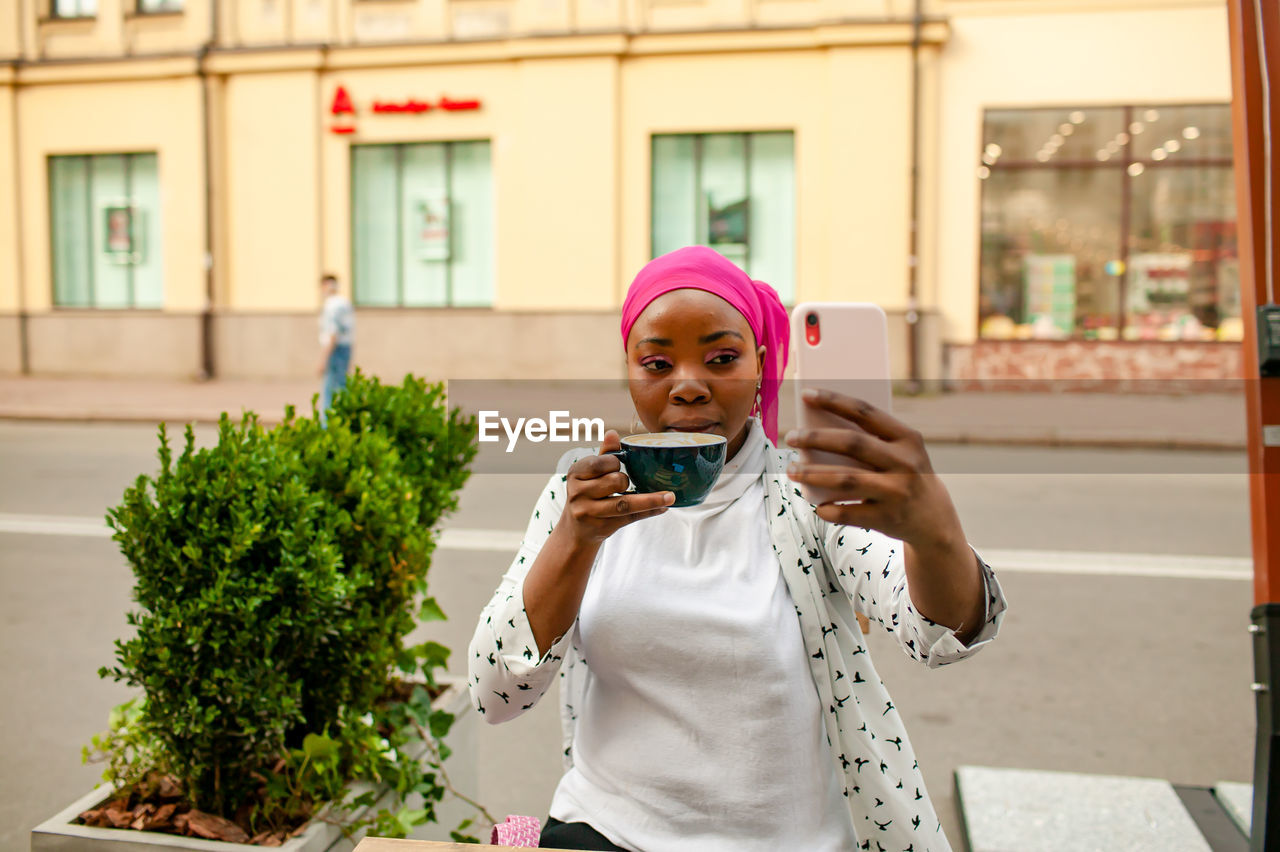 Young african muslim woman making selfie in outdoor cafe