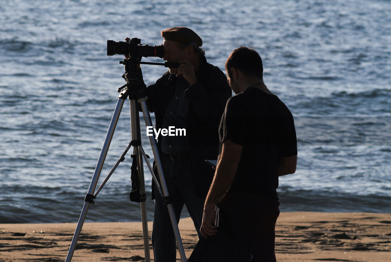 Cinematographic set, backlit cameramen with sunset sea background