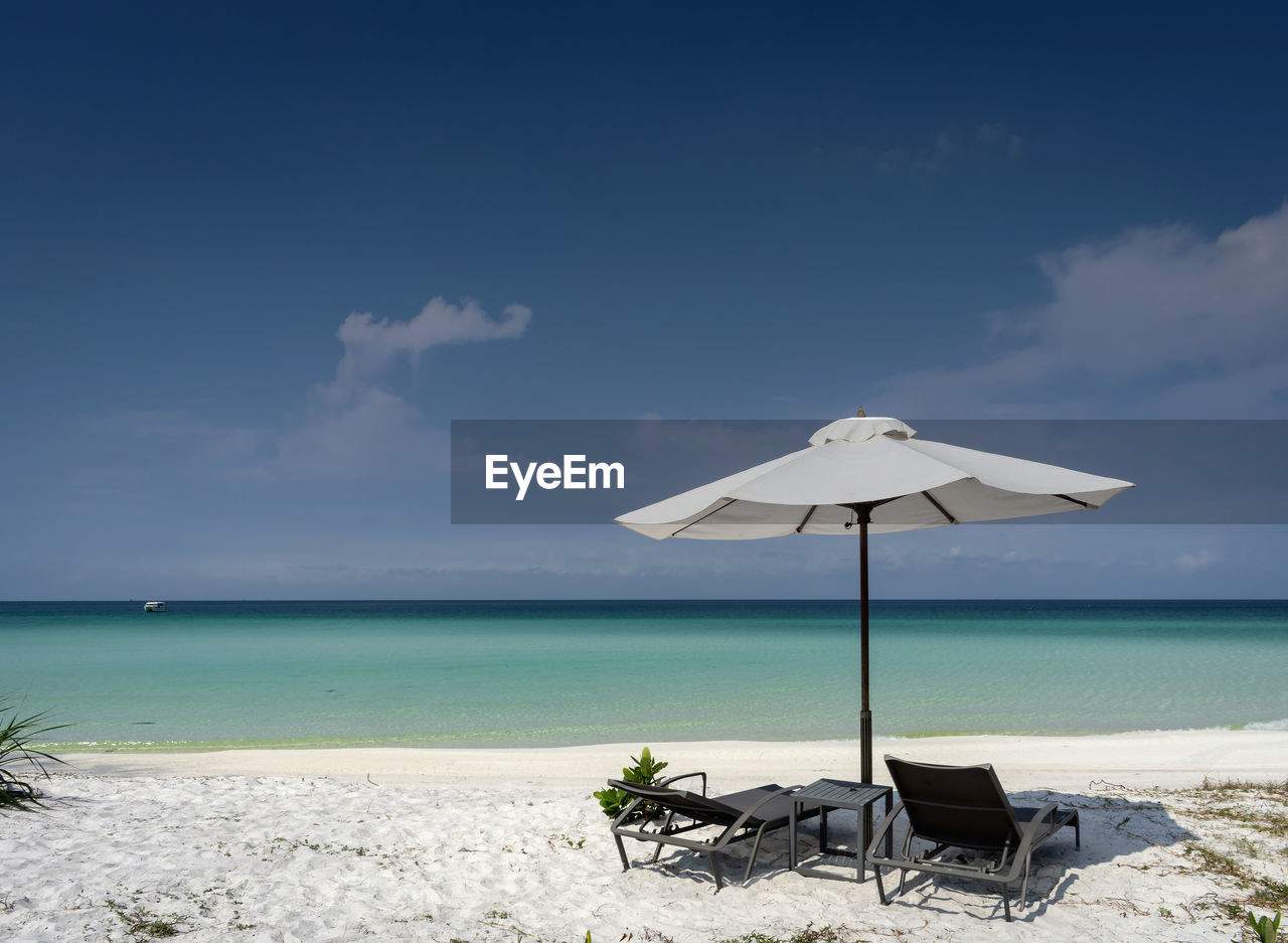 DECK CHAIRS BY BEACH AGAINST SKY