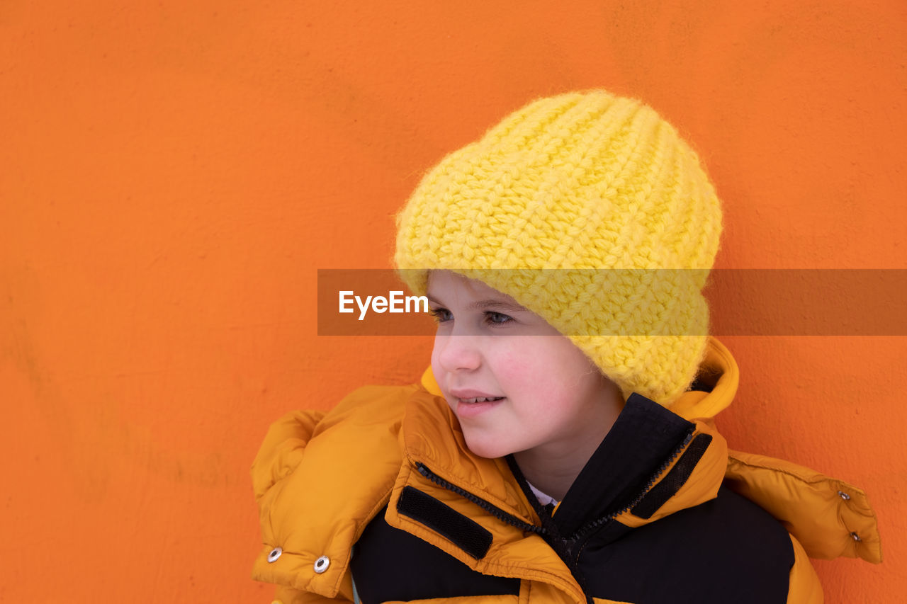portrait of cute girl wearing hat against yellow background