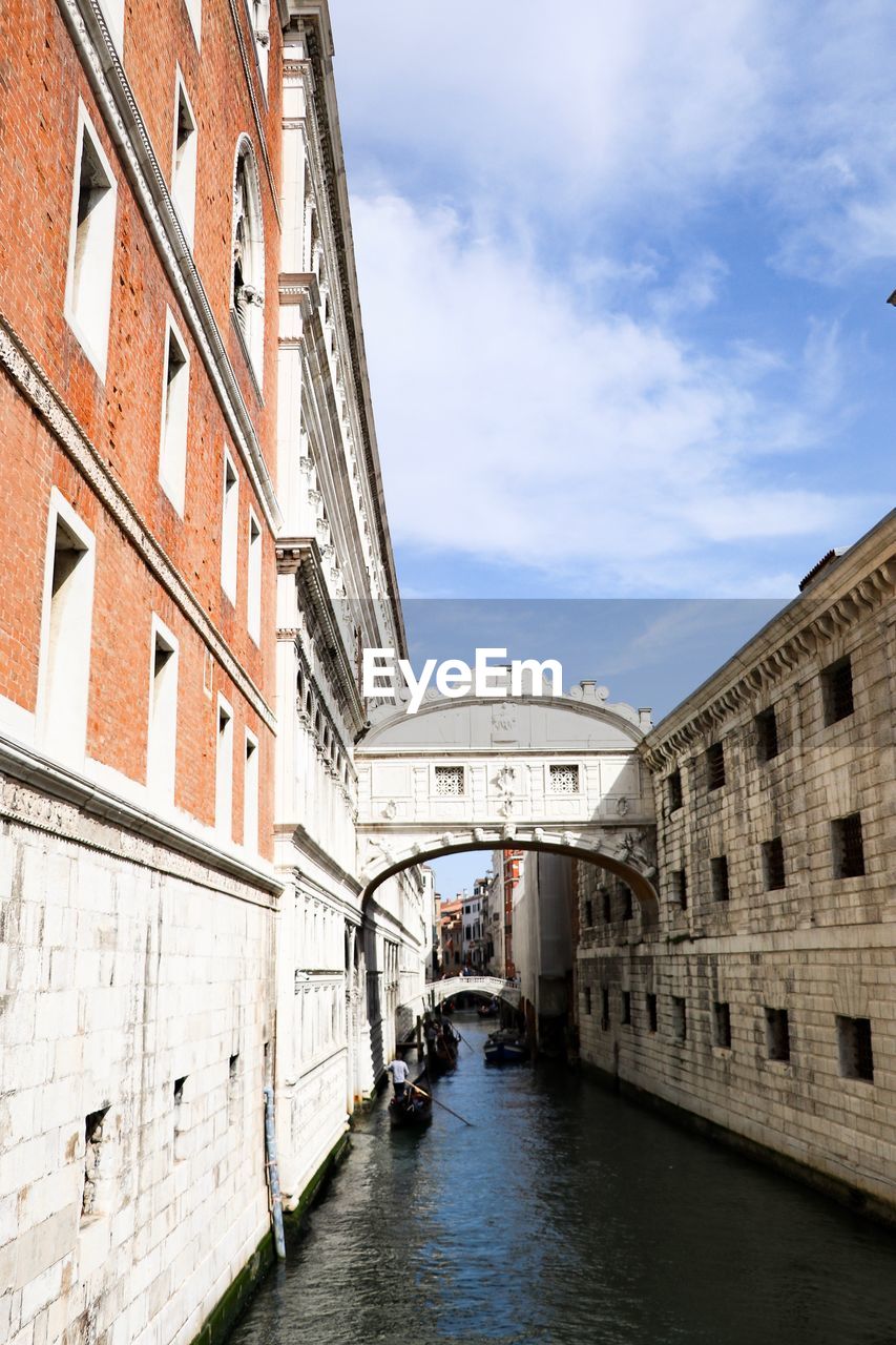 Canal amidst buildings in city against sky