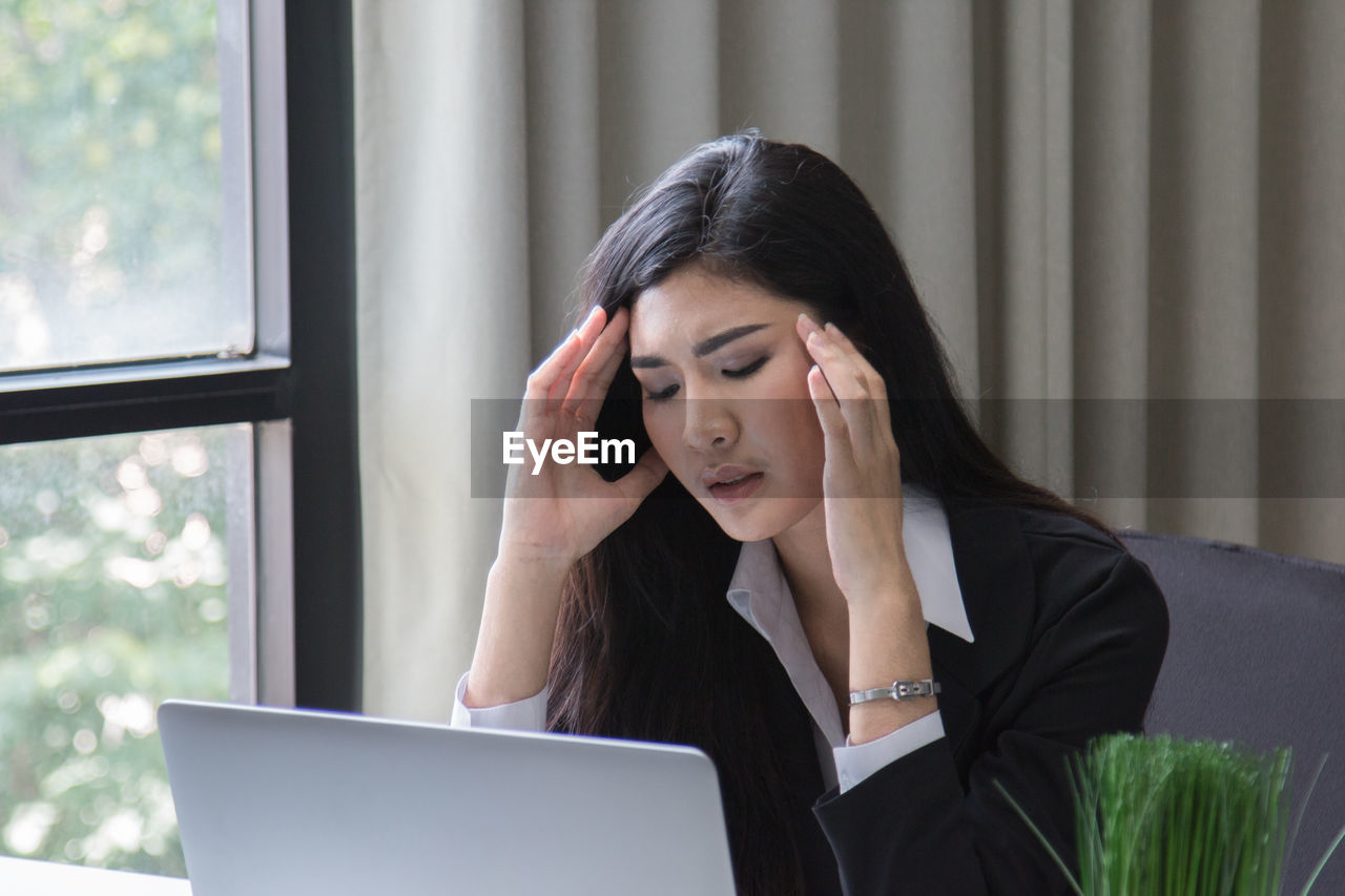 Businesswoman using laptop while working in office