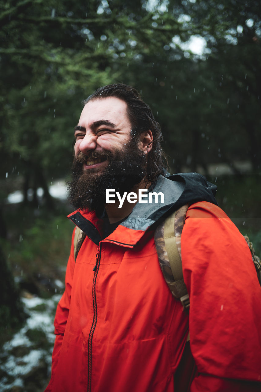 Bearded man in nature during a snowy day smiling happily