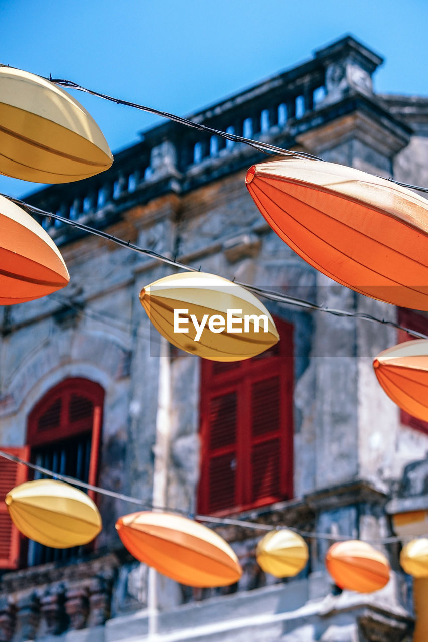 Low angle view of lanterns hanging by building against sky