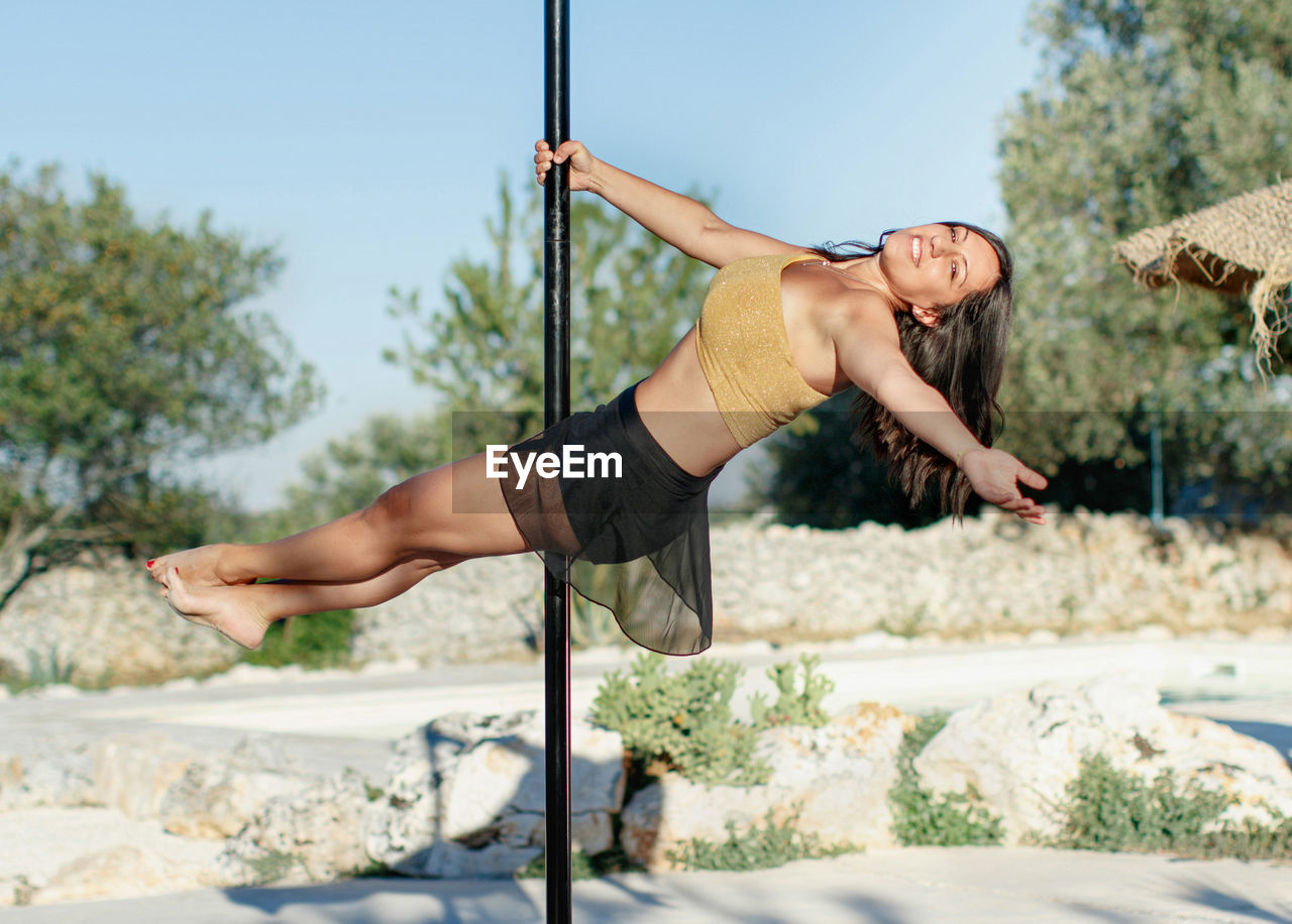 Portrait of young woman dancing on pole outdoors