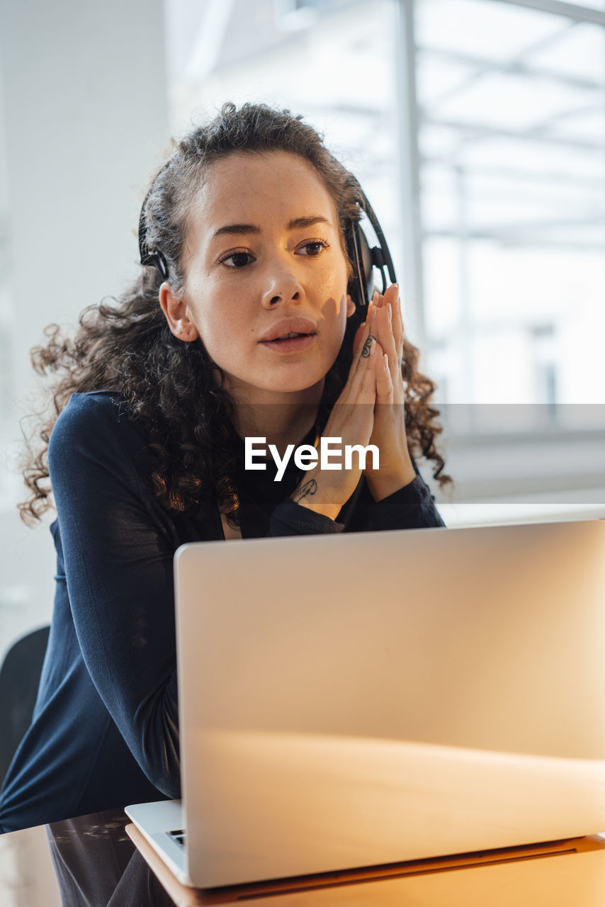 Customer service representative with laptop sitting at desk in office