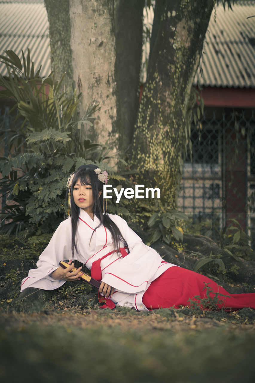 Young woman wearing traditional clothing while sitting on land