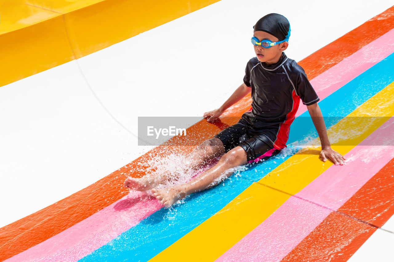 Boy sitting on slide at water park