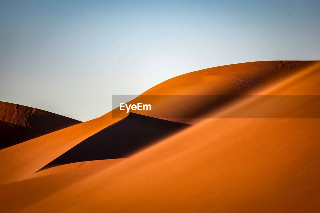 Low angle view of sand dunes against sky