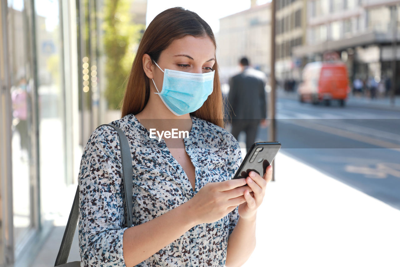 Young woman using mobile phone in city