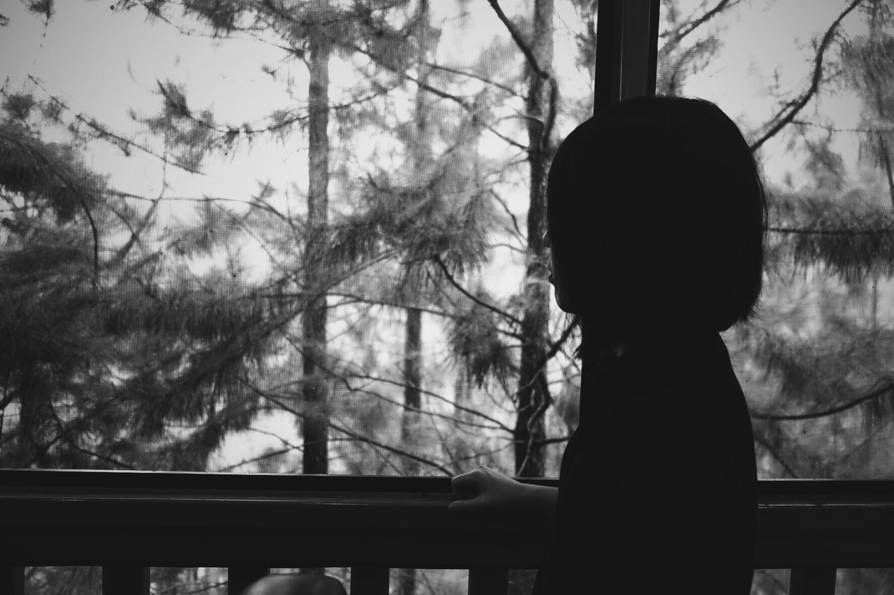 Side view of woman looking at trees from balcony