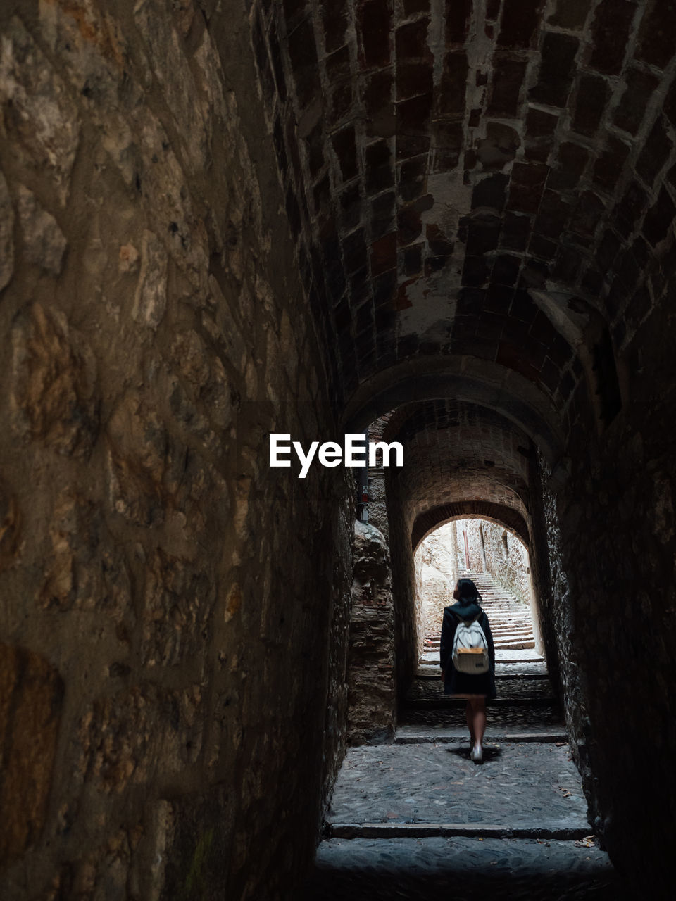 Woman walking in dark tunnel