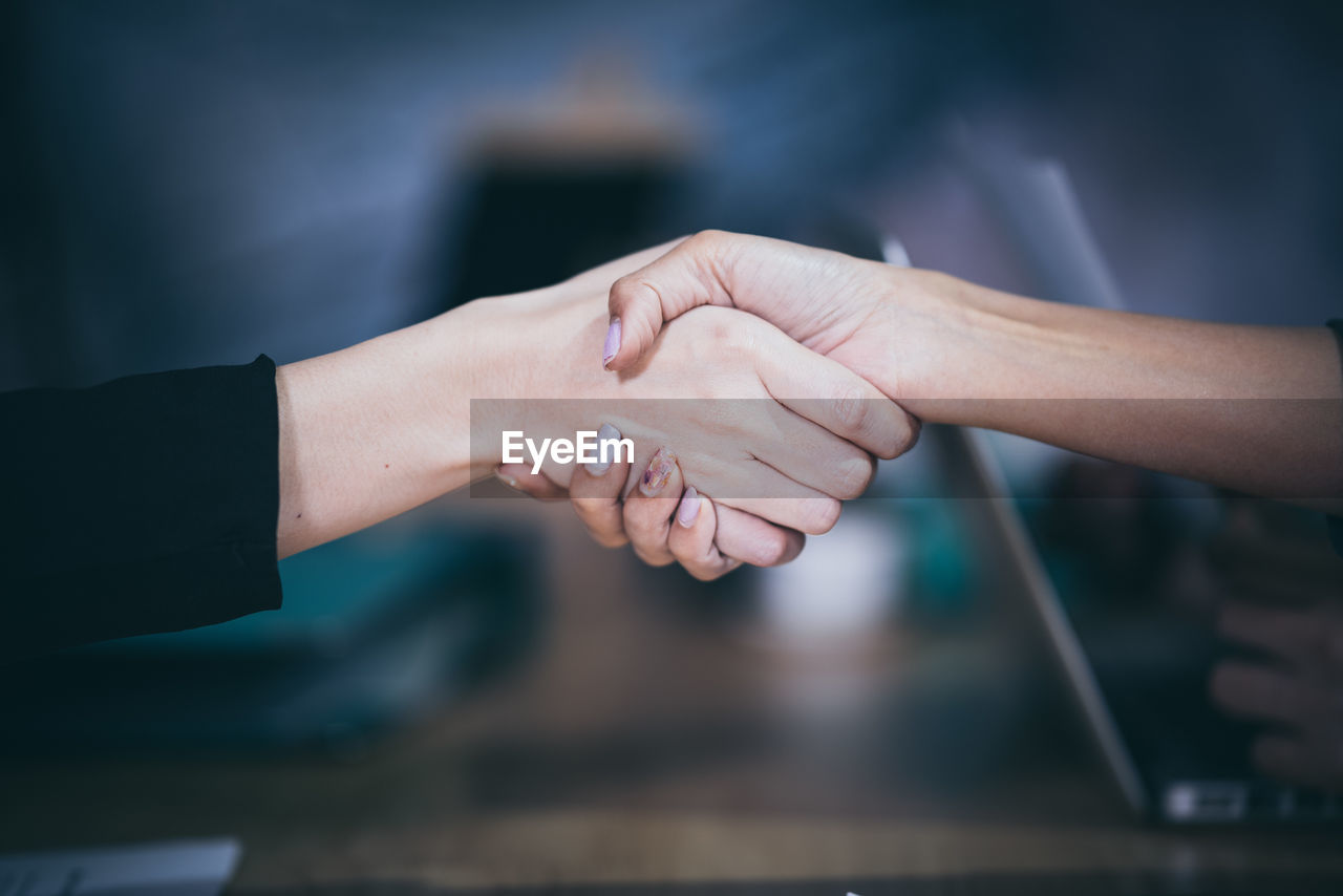 Cropped image of businesswomen shaking hands in office