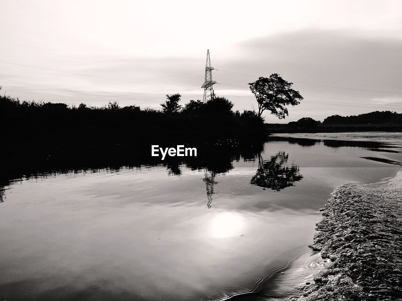 REFLECTION OF SILHOUETTE TREES IN LAKE AGAINST SKY DURING SUNSET