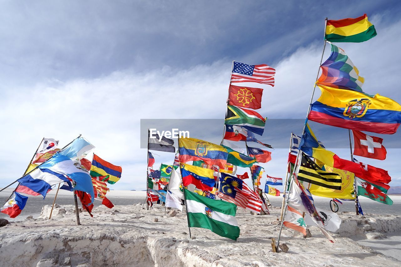 Colorful flags on rock against cloudy sky