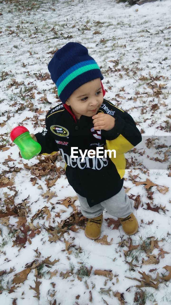 Boy in warm clothing standing on snowy field