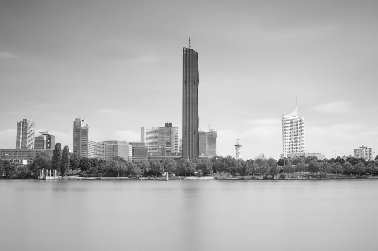 Sea by cityscape against sky