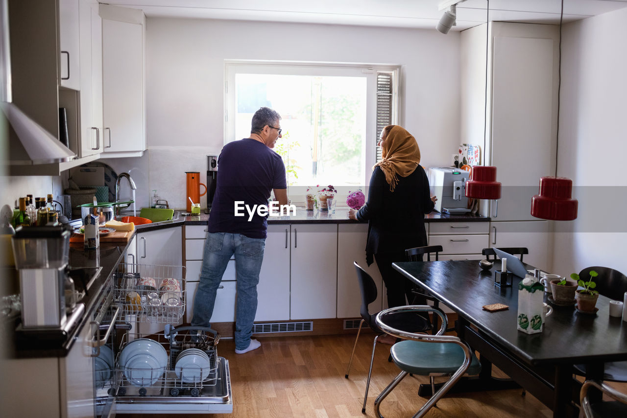 Rear view of couple standing in kitchen