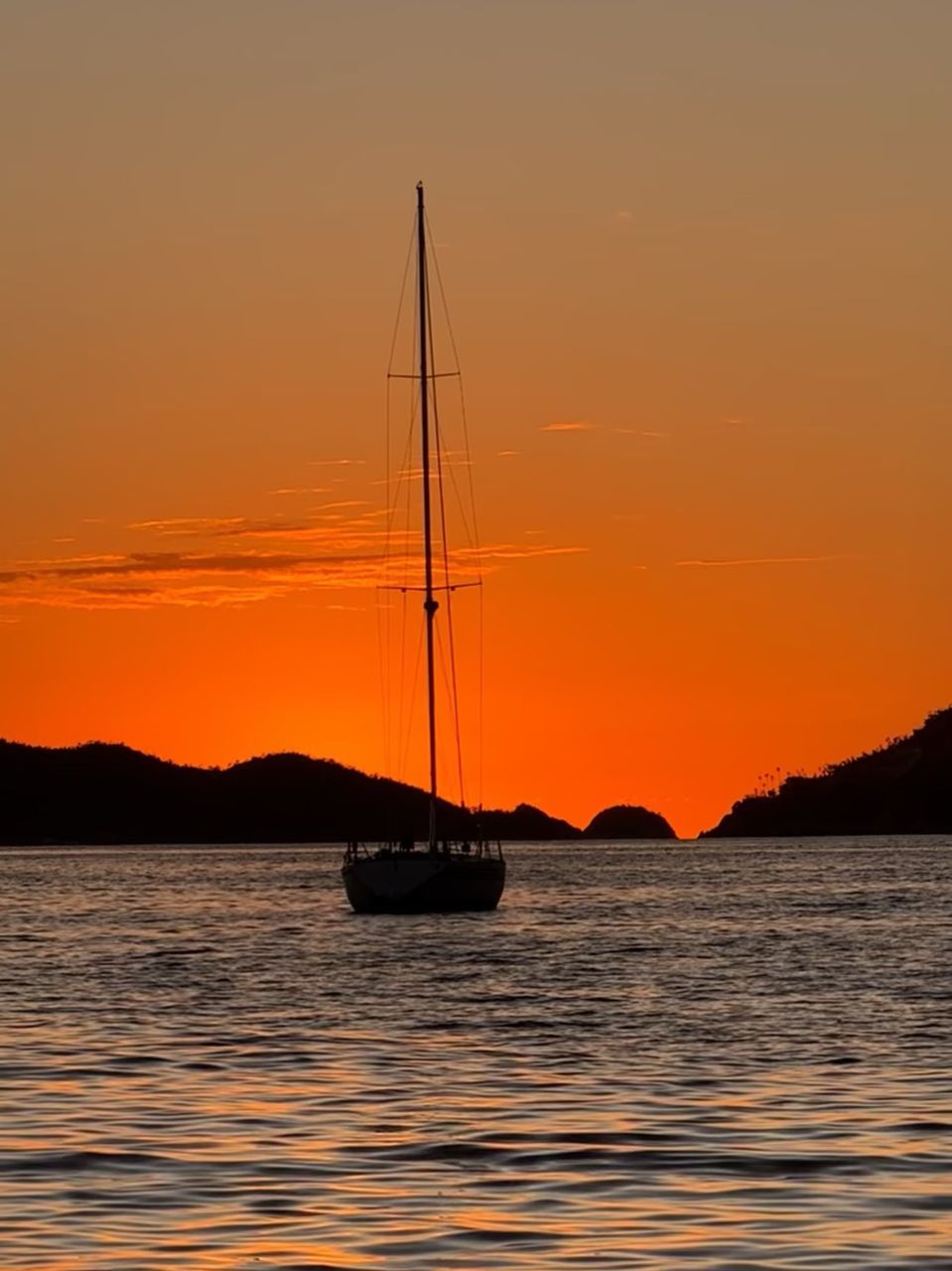 water, sunset, sea, nautical vessel, transportation, sky, sailboat, mode of transportation, beauty in nature, sailing, horizon, nature, boat, vehicle, scenics - nature, ship, silhouette, dusk, orange color, ocean, sailing ship, mast, travel, tranquility, afterglow, tranquil scene, pole, bay, no people, coast, idyllic, evening, watercraft, outdoors, travel destinations, environment, sun, dramatic sky, reflection, shore, yacht, vacation, holiday, mountain, trip, tall ship