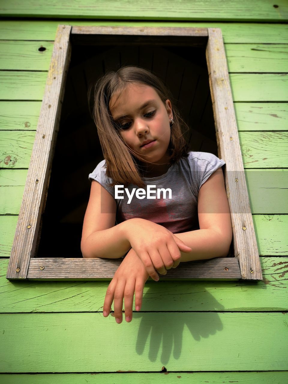 Low angle view of thoughtful girl on window