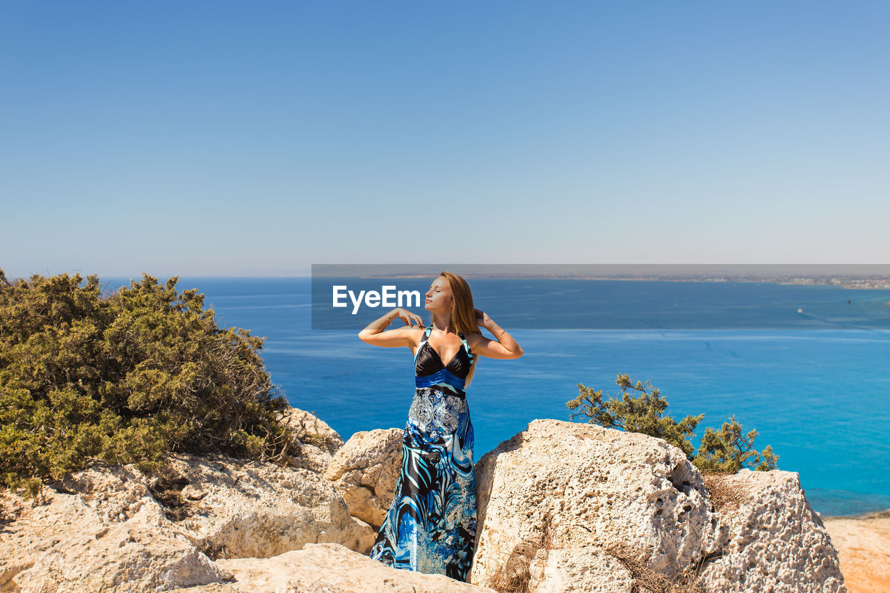 WOMAN LOOKING AT SEA AGAINST SKY