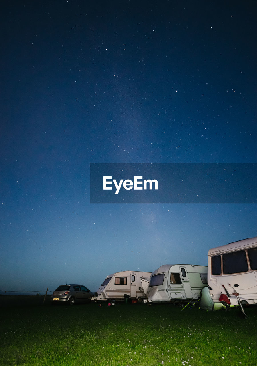 Scenic view of motor home on field against sky at night