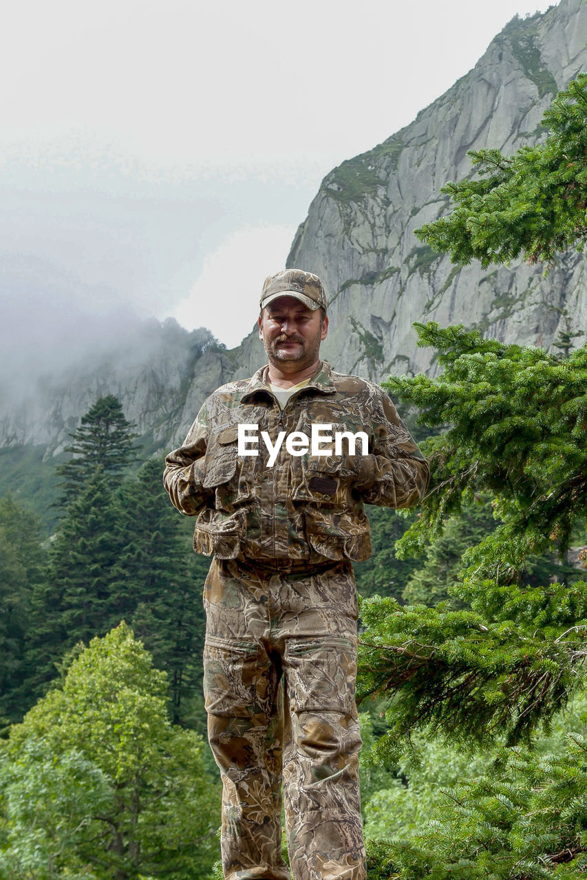 Mid adult man standing by tree against mountain