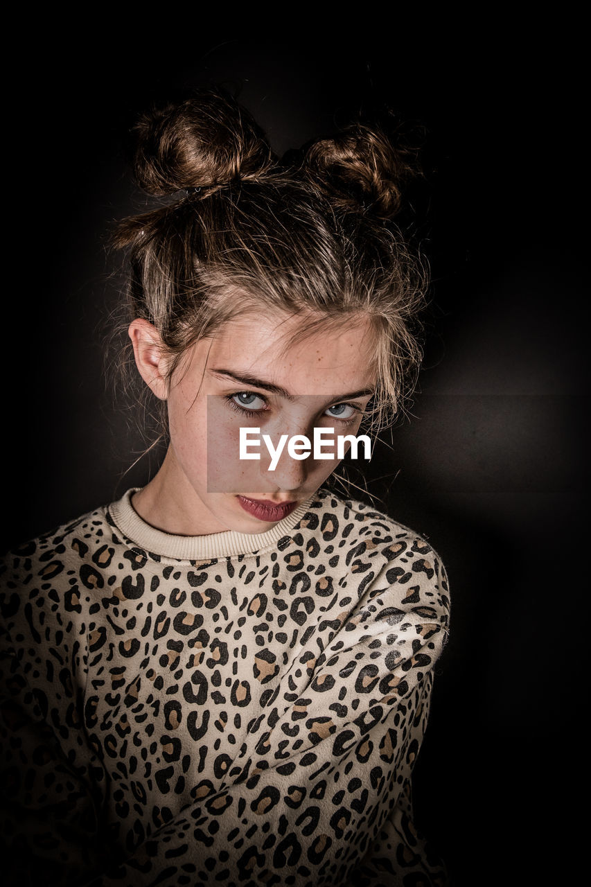 Portrait of young woman against black background