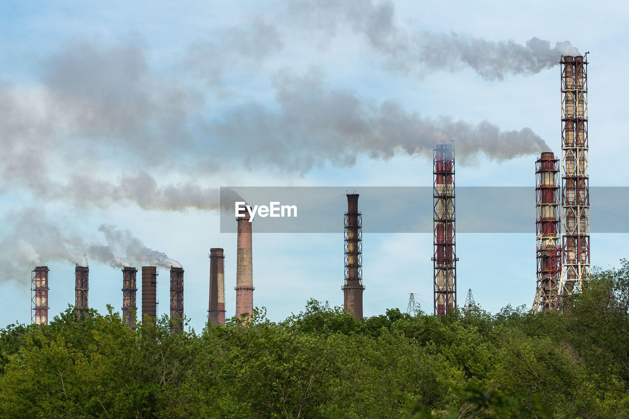 Smoke emitting from factory against sky