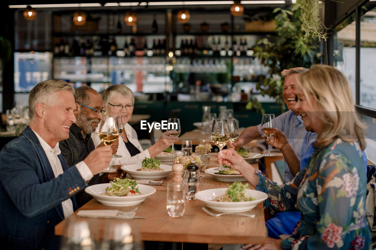 Happy senior male and female friends toasting wineglasses in restaurant