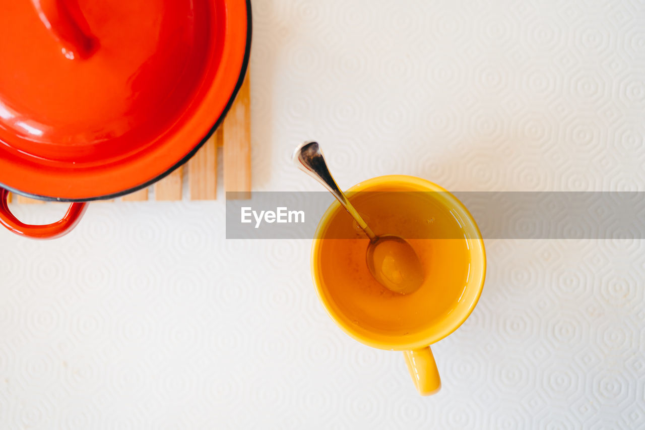 High angle view of yellow mug with a drink on table