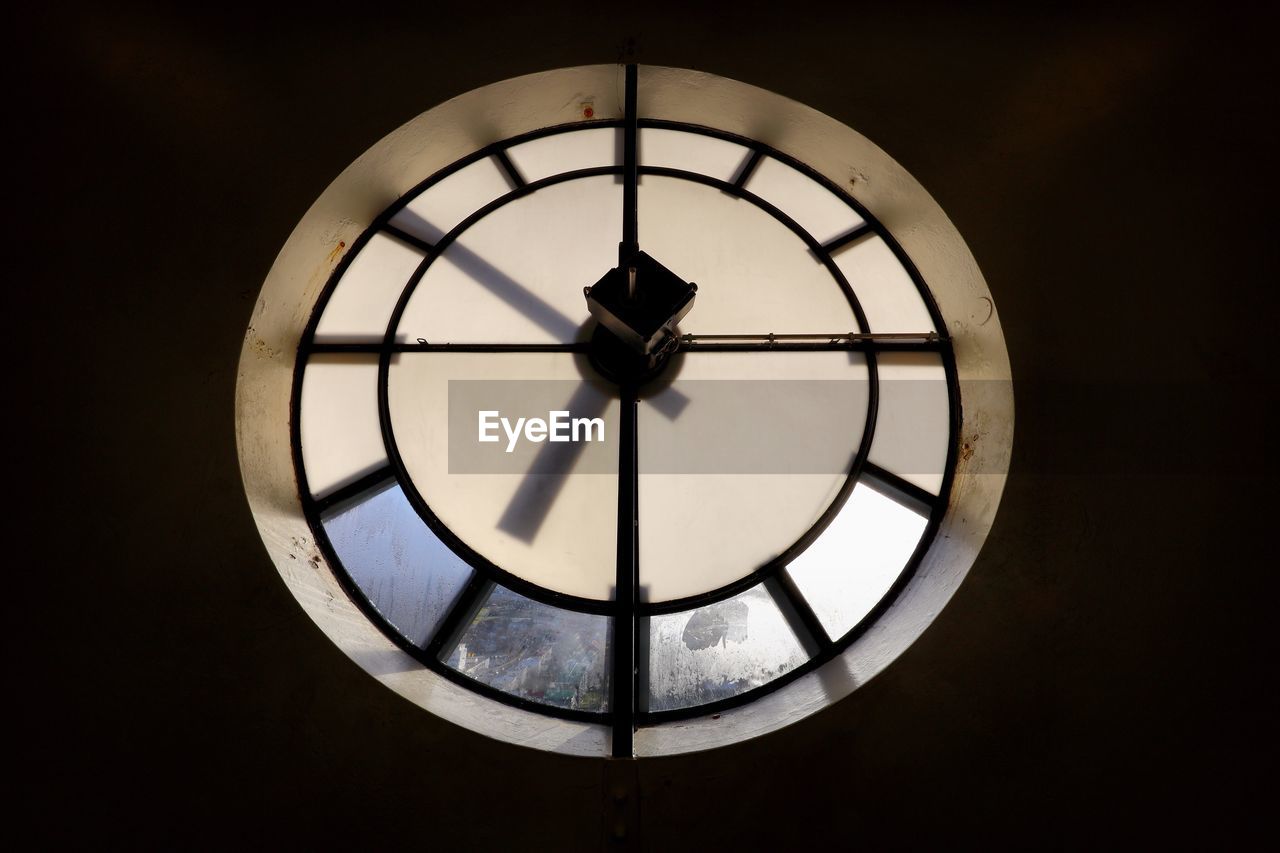 Low angle view of clock hanging against sky