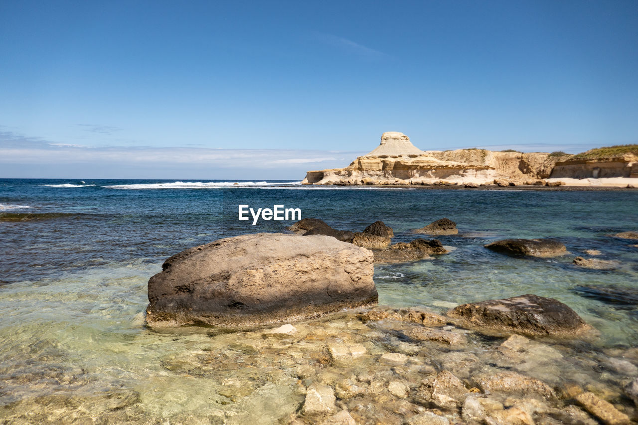 Rock formation on beach against sky