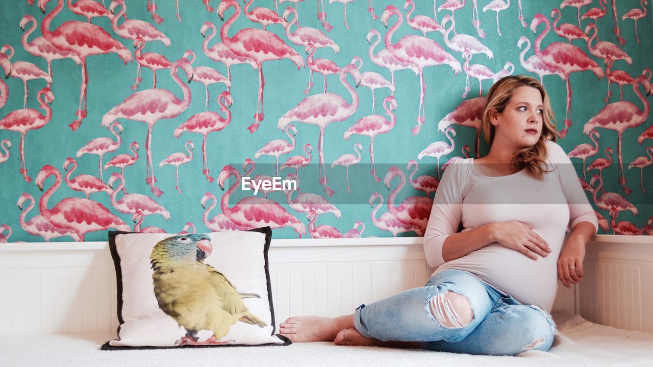 YOUNG WOMAN WITH DOG SITTING ON BED