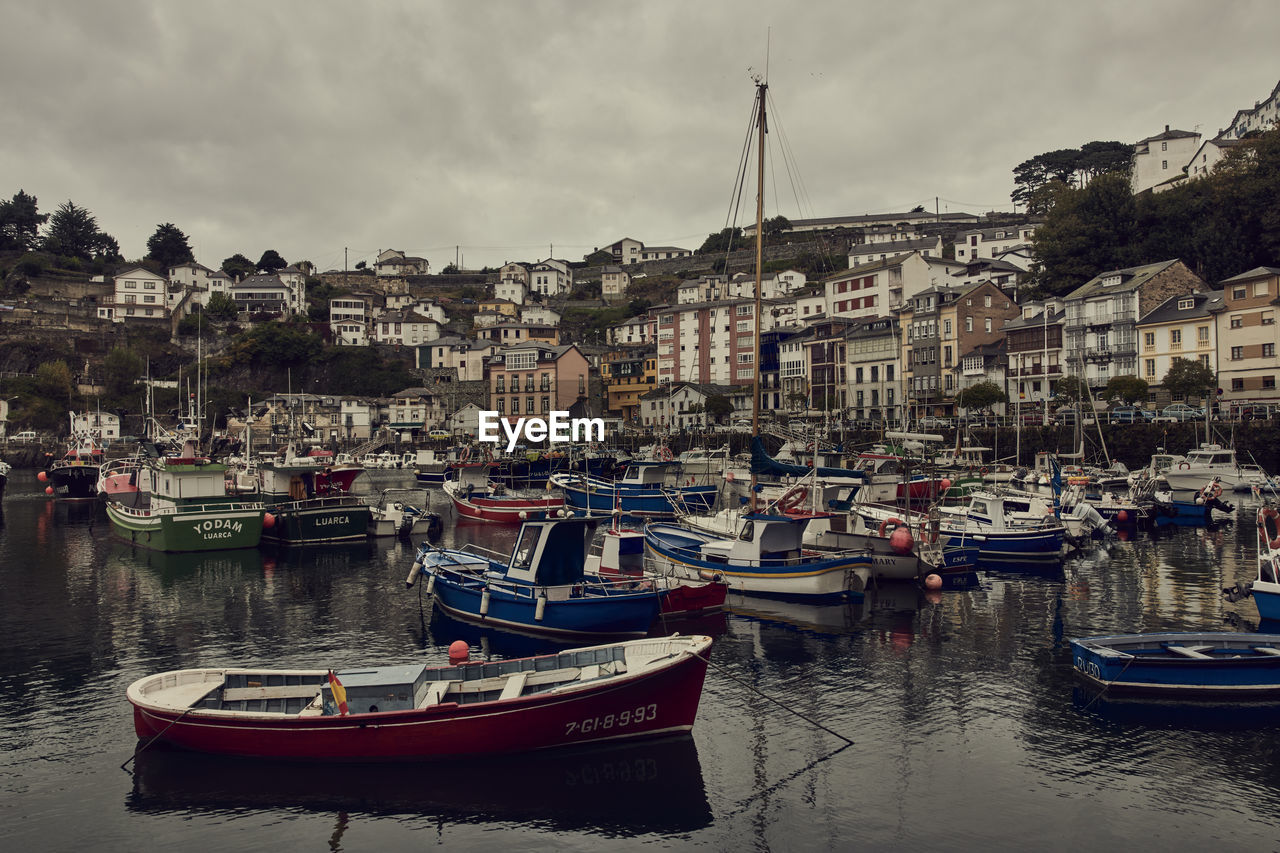 BOATS MOORED IN RIVER AGAINST BUILDINGS IN CITY