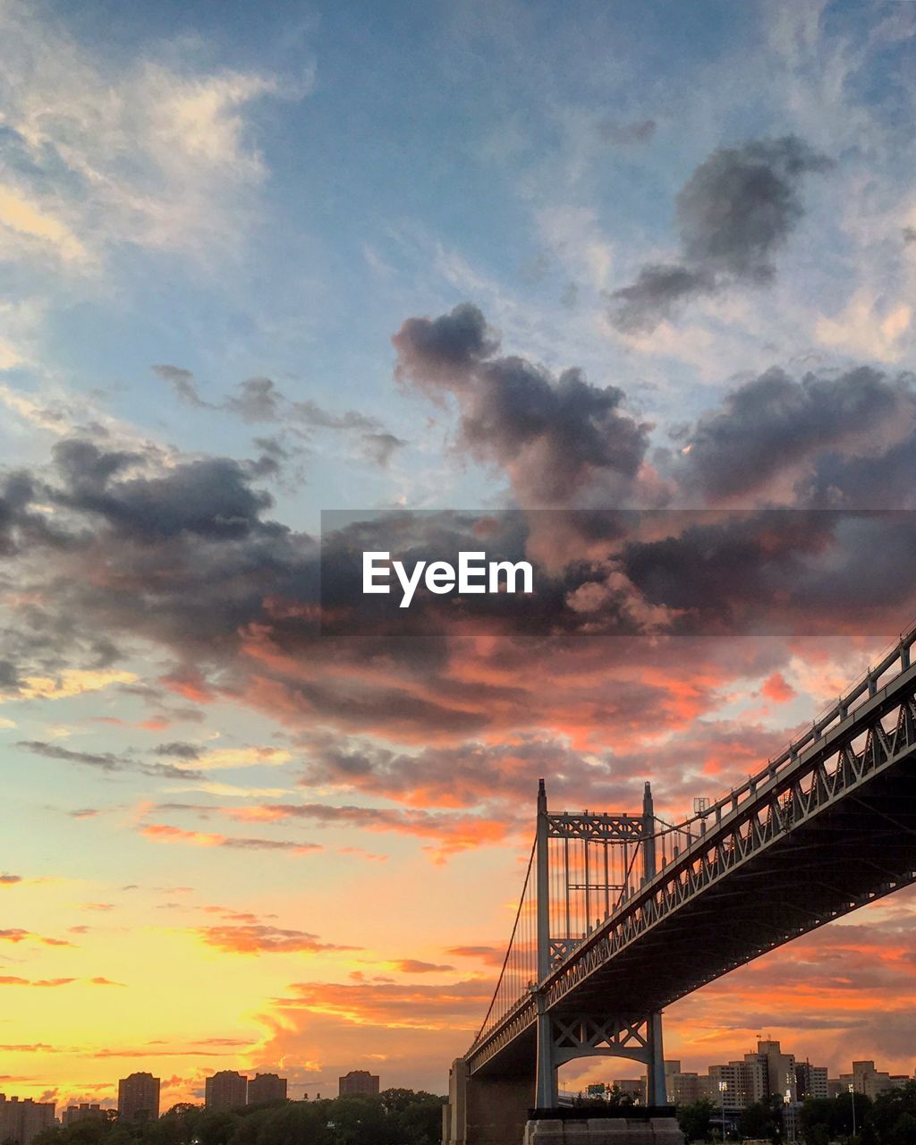 LOW ANGLE VIEW OF SUSPENSION BRIDGE AGAINST CLOUDY SKY DURING SUNSET
