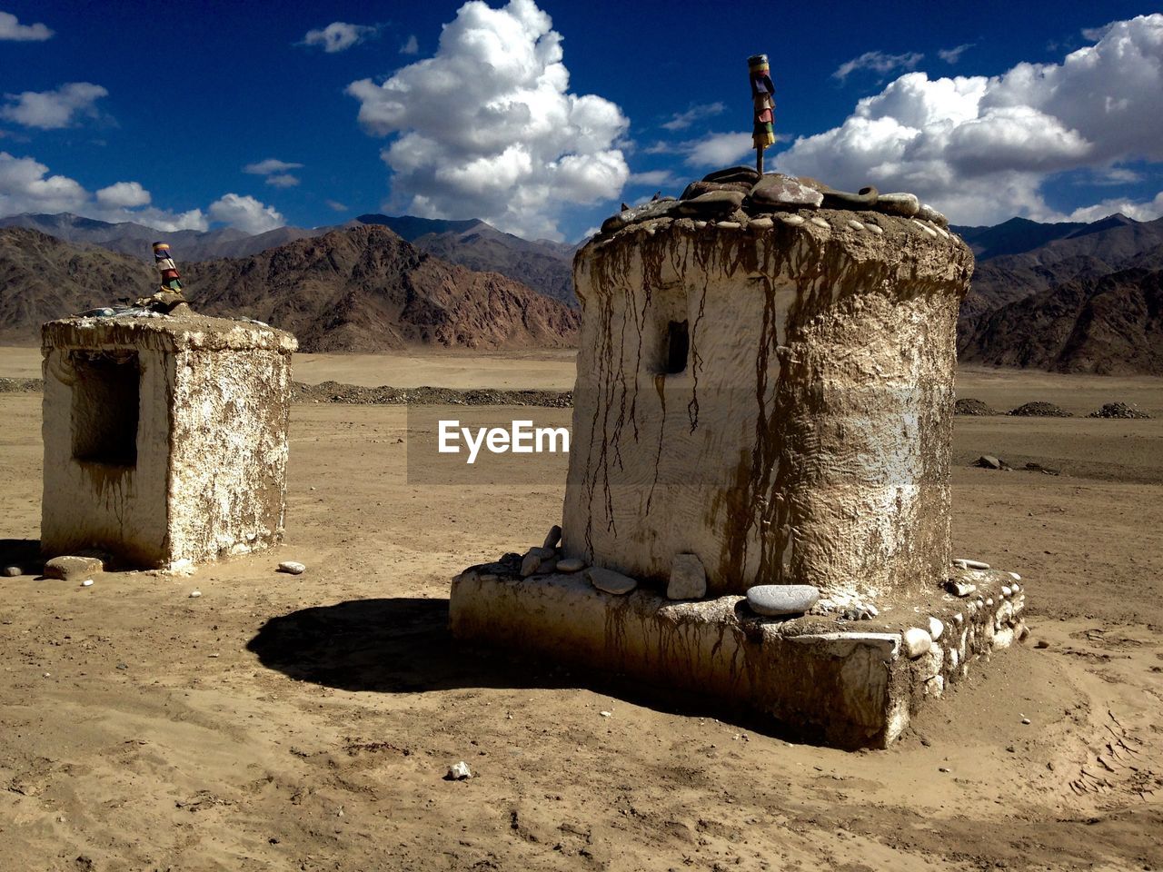 OLD RUINS ON FIELD BY MOUNTAINS AGAINST SKY