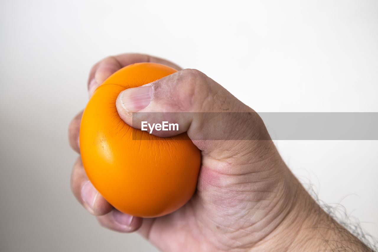 hand, holding, food, food and drink, yellow, one person, healthy eating, studio shot, orange color, close-up, wellbeing, fruit, indoors, egg, plant, adult, freshness, orange, produce, egg yolk, cut out, men