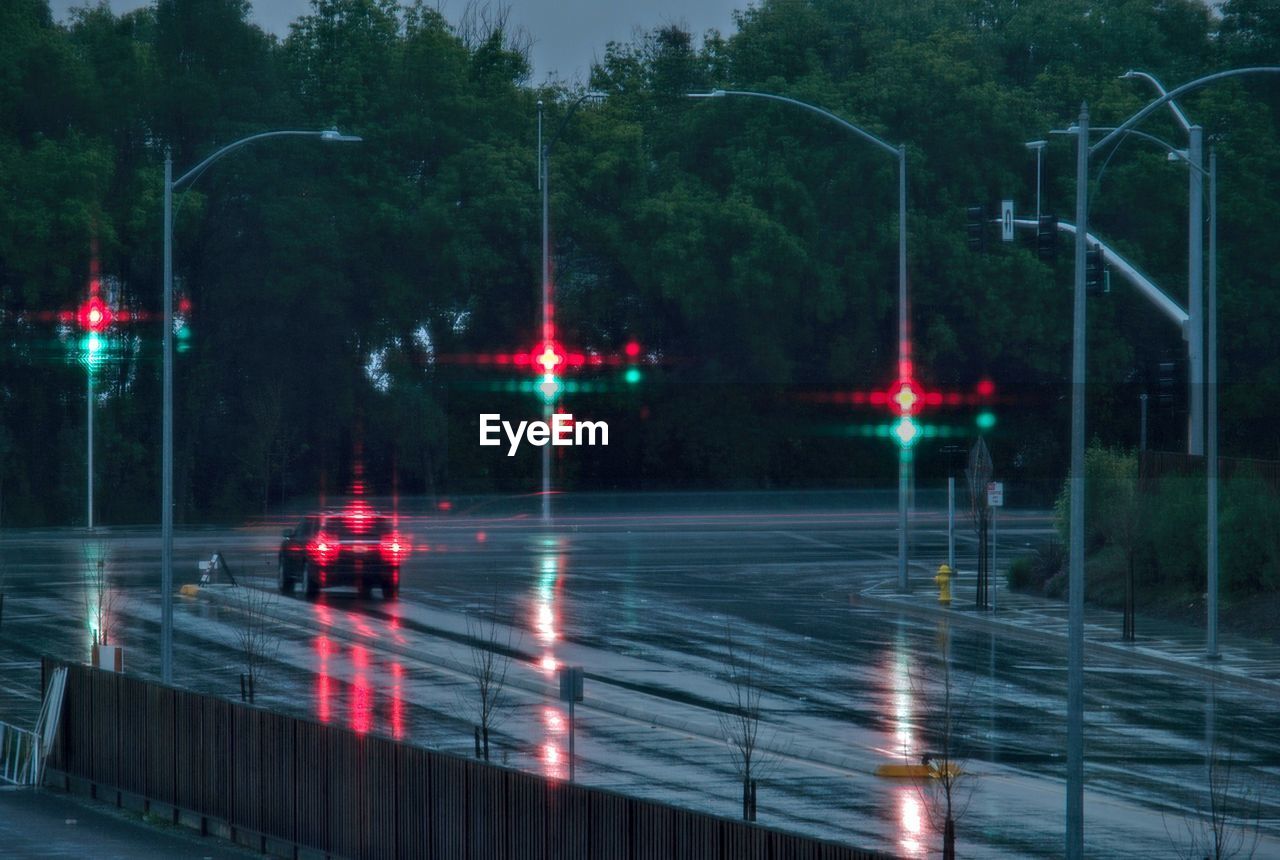 Illuminated car moving on wet street during monsoon at dusk