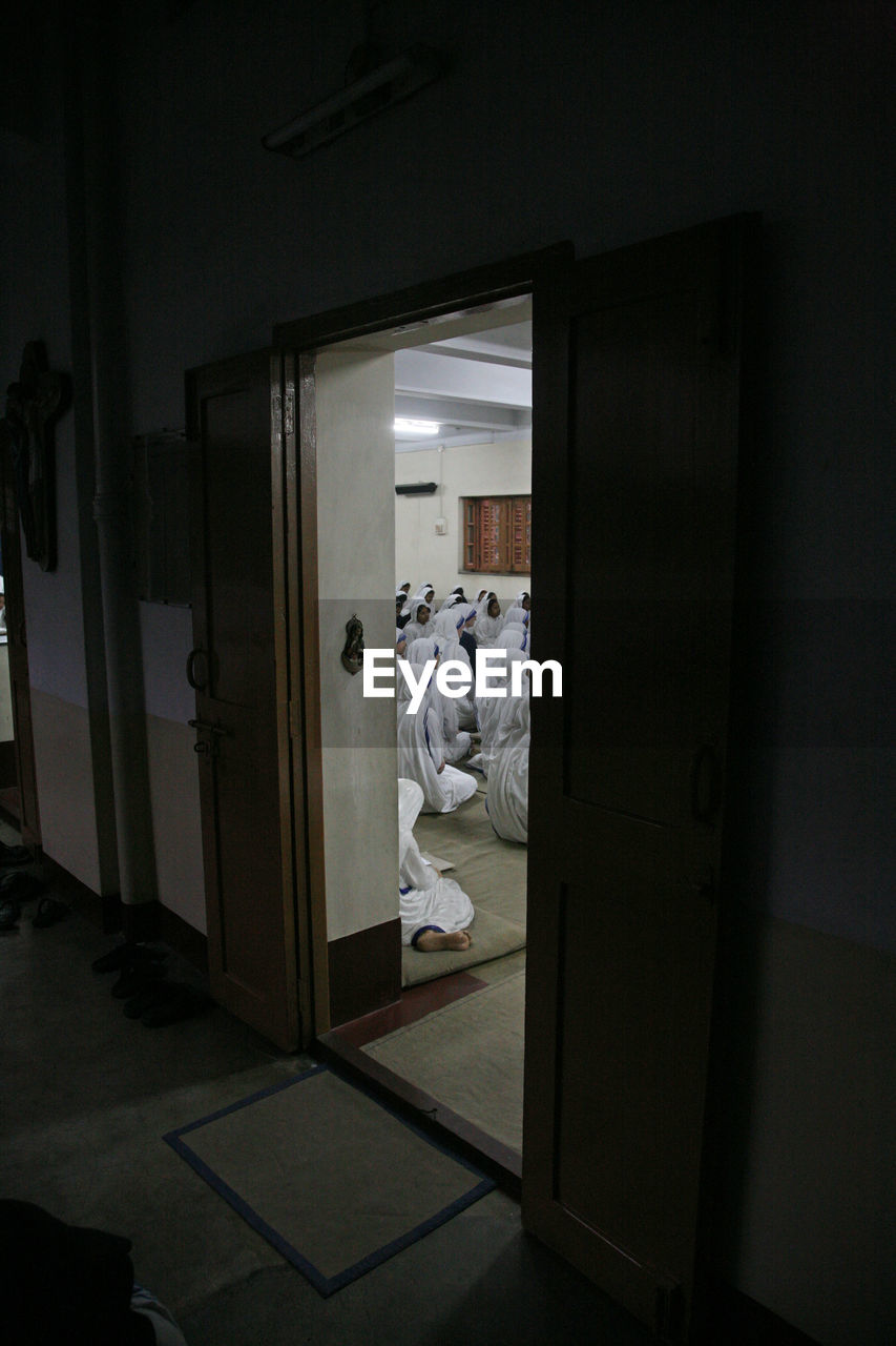 PEOPLE IN ILLUMINATED BUILDING SEEN THROUGH DOOR